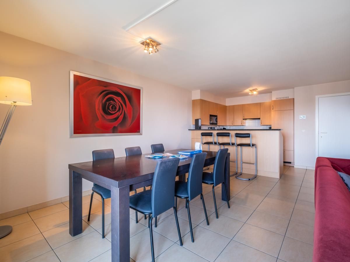 Ruime eetkamer en keuken in vakantiehuis Paco Vierde, Koksijde, West-Vlaanderen. Gezellige binnenruimte met moderne inrichting en kunstwerk.