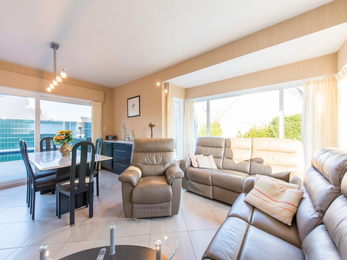 Gezellige woonkamer in vakantiehuis Mallory, Koksijde, met comfortabele banken en veel natuurlijk licht, ideaal voor ontspanning in West-Vlaanderen.