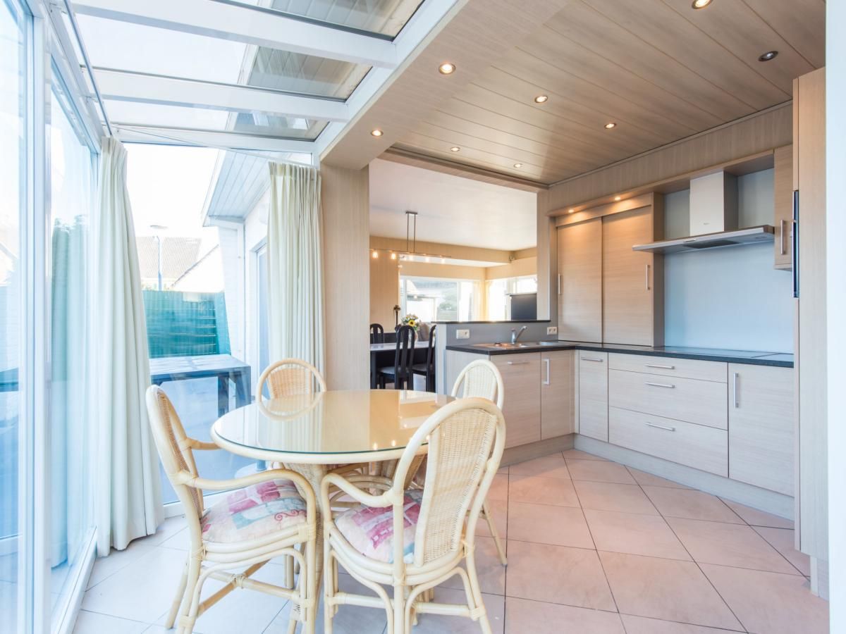 Lichte keuken en eetruimte in vakantiehuis Mallory, Koksijde, West-Vlaanderen. Moderne inrichting met glazen dak en gezellige eethoek.
