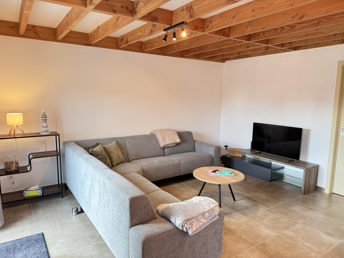 Gezellige woonkamer van vakantiehuis Westhinder II H23 in Koksijde, West-Vlaanderen, met comfortabele zithoek en moderne inrichting.