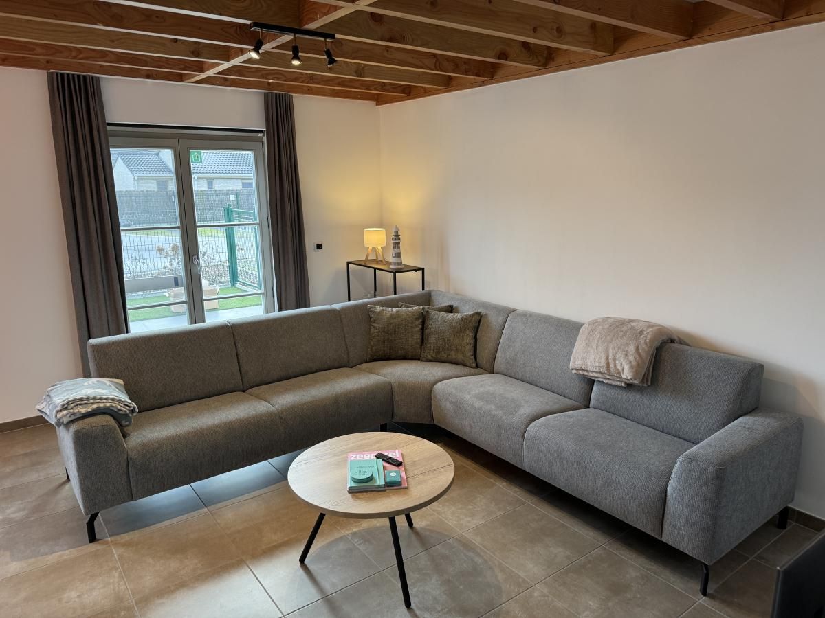 Gezellige woonkamer in vakantiehuis Westhinder II H23, Koksijde, met comfortabele zithoek en moderne inrichting.
