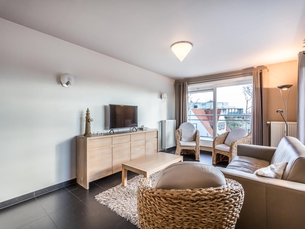 Stijlvolle woonkamer van Le Penthouse vakantiehuis in Koksijde, West-Vlaanderen, met comfortabele zithoek en uitzicht op de omgeving.