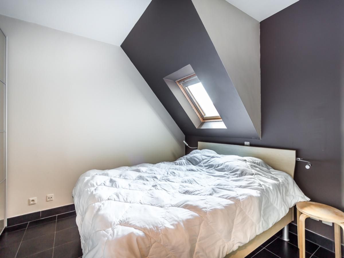 Sfeervolle slaapkamer in Le Penthouse, een vakantiehuis in Koksijde, West-Vlaanderen, met een dakraam voor natuurlijk licht.