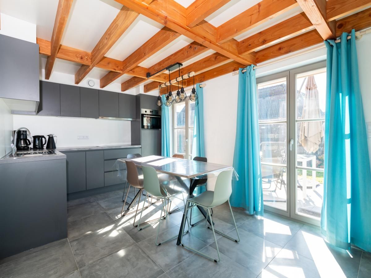 Moderne keuken en eetruimte in vakantiehuis Westhinder I H12, Koksijde, West-Vlaanderen, met houten balken en veel natuurlijk licht.