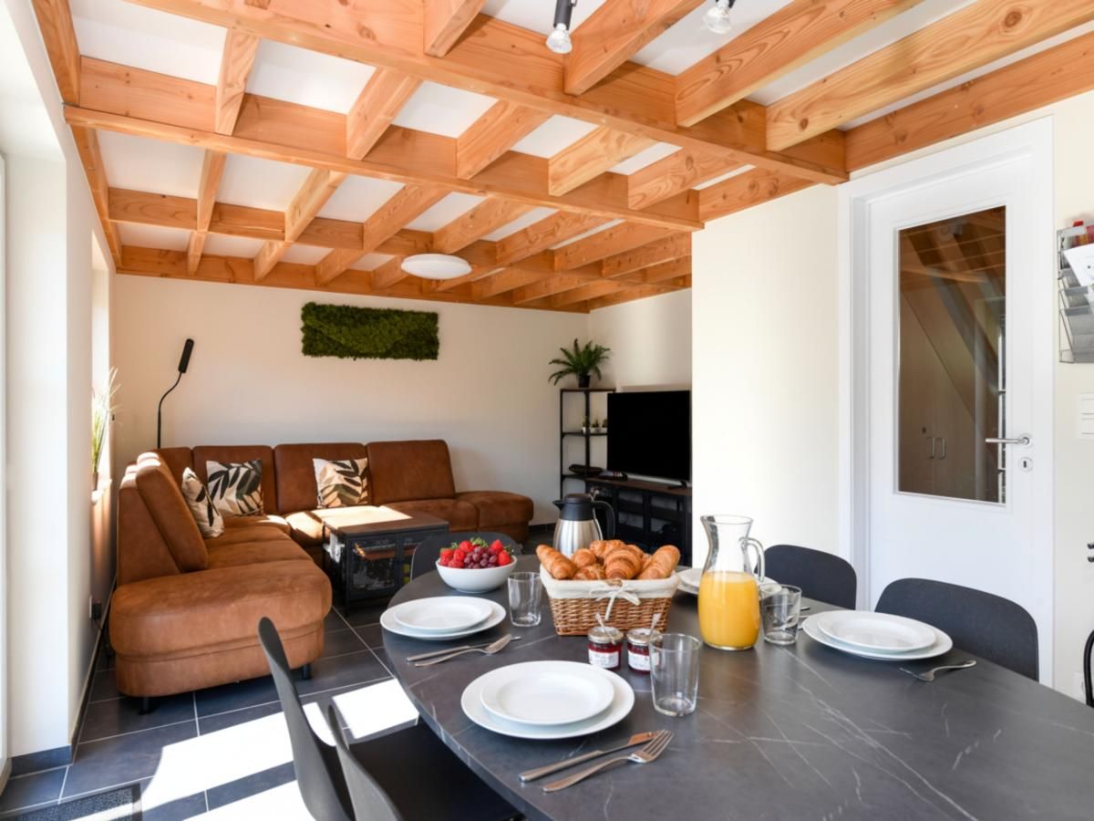 Gemuetliches Wohnzimmer im Ferienhaus Westhinder II H53, Koksijde, mit Holzbalkendecke und geraeumiger Essecke fuer einen entspannten Aufenthalt.