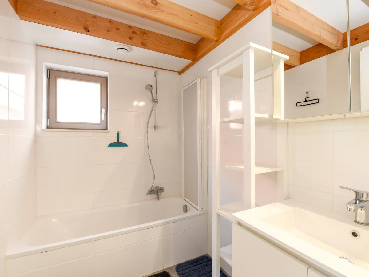Moderne badkamer in vakantiehuis Westhinder II H54, Koksijde, West-Vlaanderen, met houten balken en wit sanitair voor ultiem comfort.