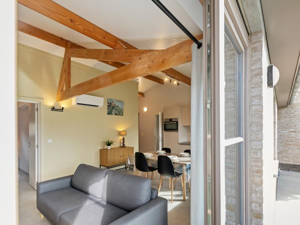 Moderne woonkamer van vakantiehuis Westhinder II H18 in Koksijde, West-Vlaanderen, met ruime zithoek en veel natuurlijk licht.