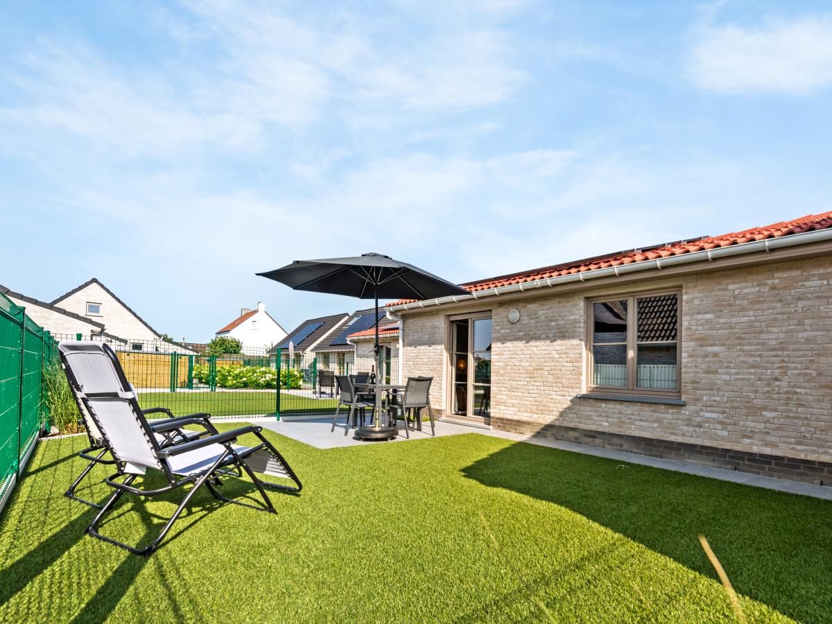 Geniessen Sie die sonnige Terrasse des Ferienhauses Westhinder II H19 in Koksijde, Westflandern, mit bequemen Sitzgelegenheiten und gruener Umgebung.