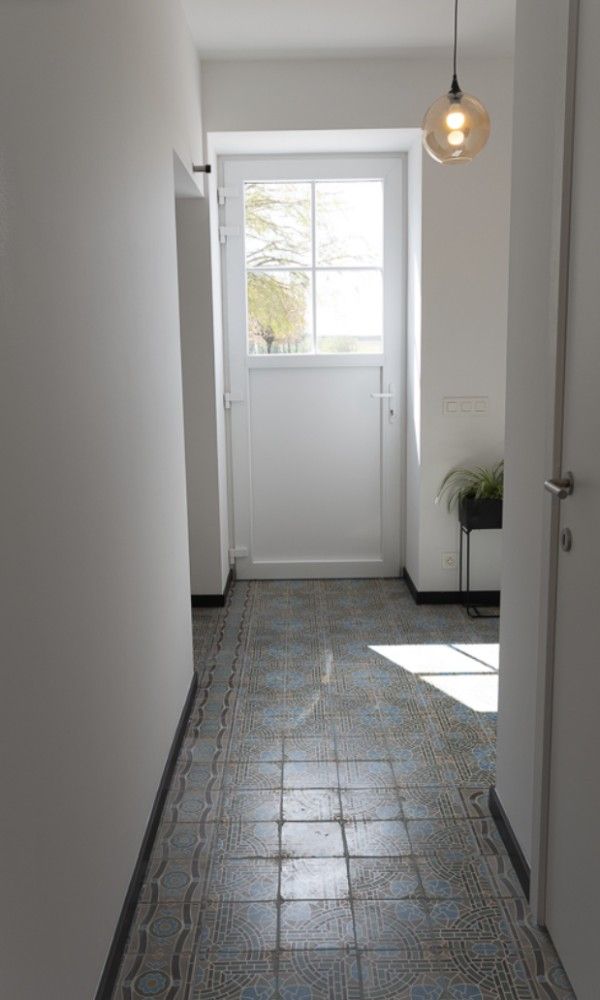 Heller Eingang zum Ferienhaus 't hov in Passendale mit stilvollem Fliesenboden und modernen Moebeln.