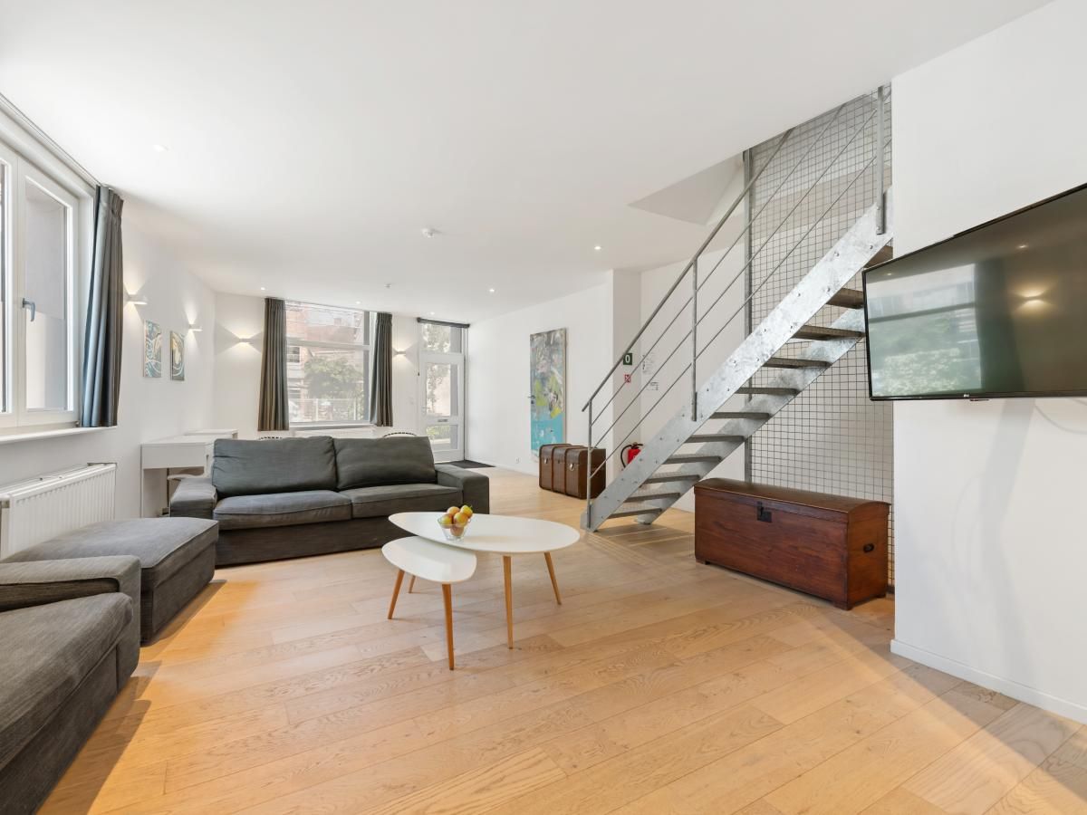 Stilvolles Wohnzimmer in "De Loft", einem Ferienhaus in Veurne, Westflandern, mit moderner Einrichtung und viel Tageslicht.
