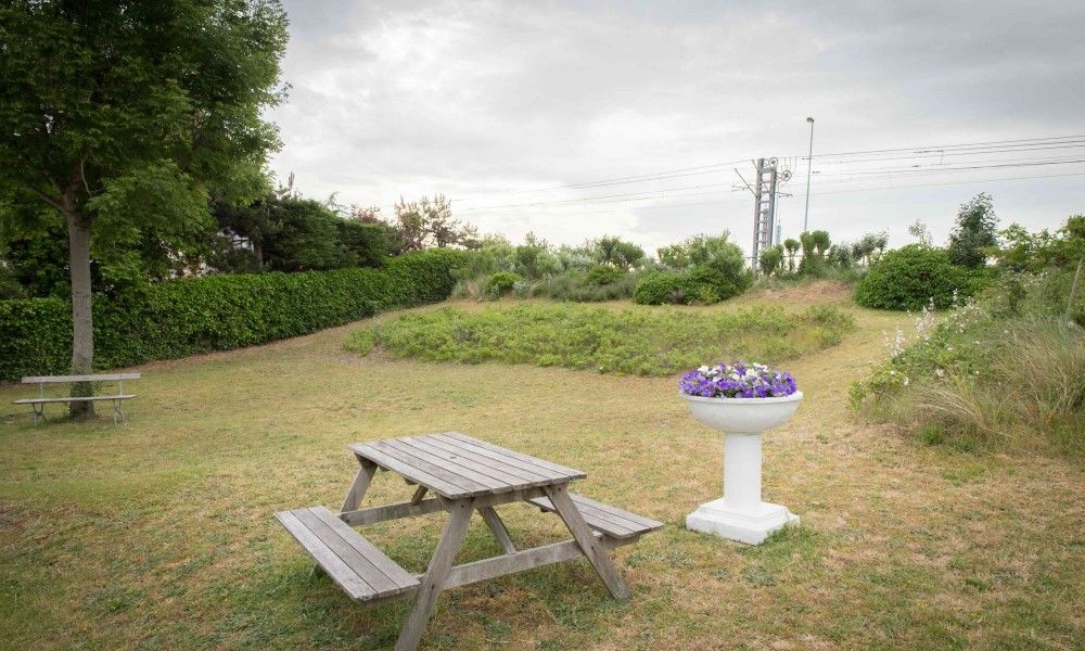 Rustieke tuin van Charmevilla Westende in Westende, Belgie, met picknicktafel en groene omgeving voor een ontspannen vakantiehuiservaring.