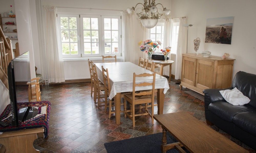 Gezellige woonkamer in Charmevilla Westende, een vakantiehuis in Westende, West-Vlaanderen, met ruime eettafel en rustieke inrichting.