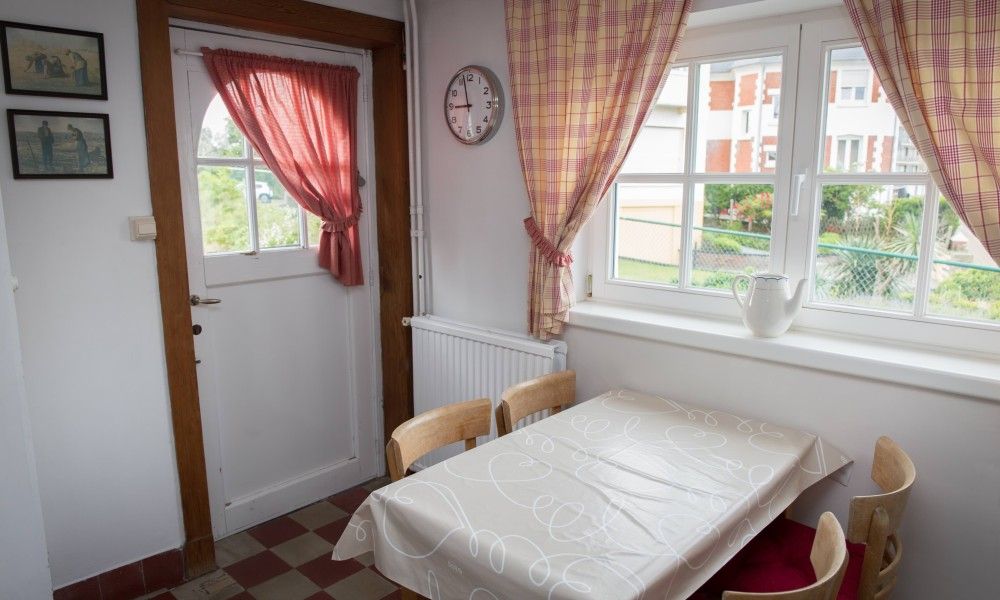Gezellige eetruimte in Charmevilla Westende, een vakantiehuis in Westende, West-Vlaanderen, met uitzicht op de groene omgeving.