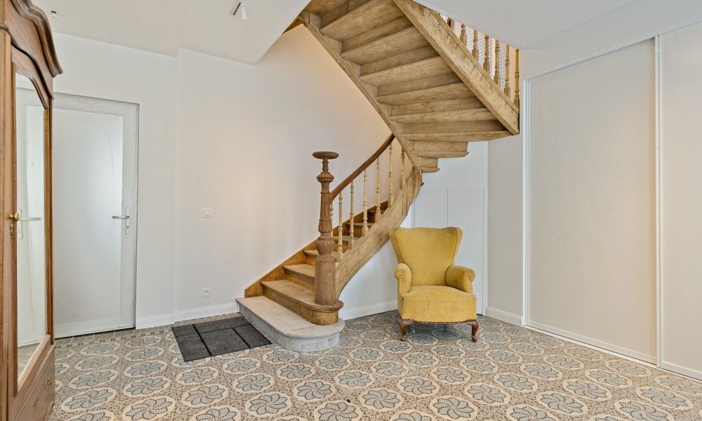 Diele von Maison Perron, Ferienhaus De Panne, Westflandern mit Holztreppe und altem Stuhl.