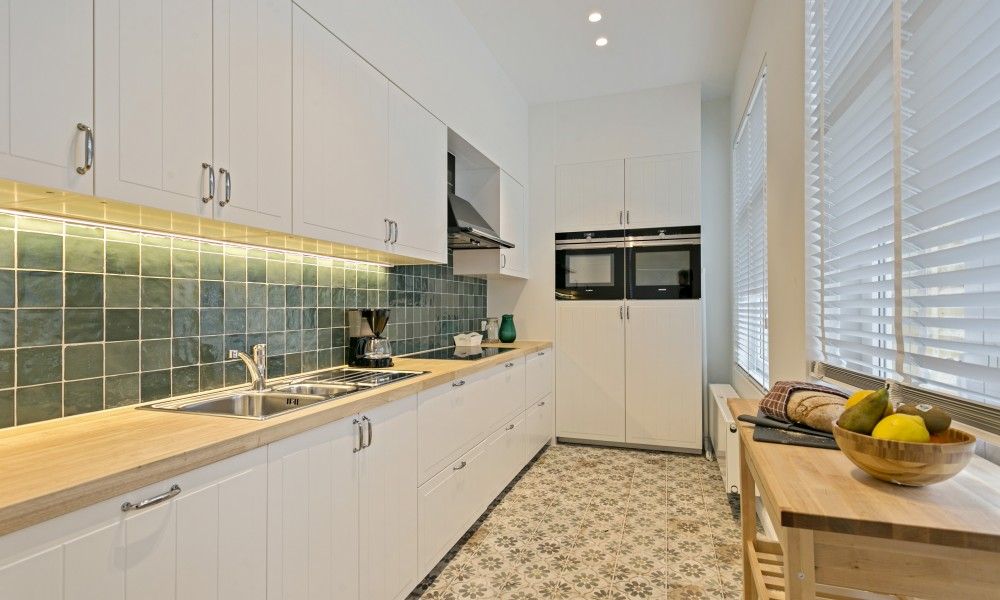 Kueche in Maison Perron, Ferienhaus De Panne, Westflandern mit modernen Geraeten und gefliestem Boden.