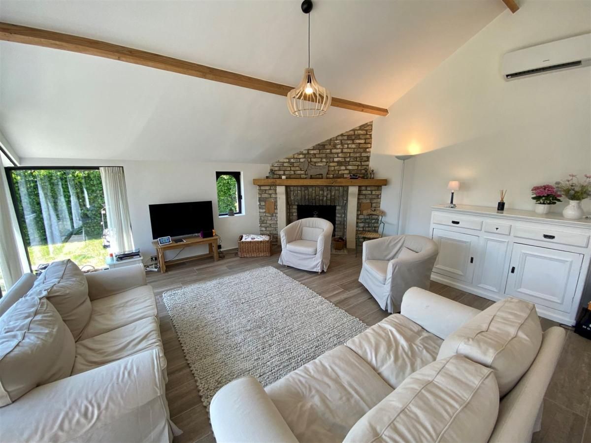 Gemuetliches Wohnzimmer des Ferienhauses Petunias Deluxe in Sint-Idesbald, Westflandern, mit Kamin und bequemer Sitzecke.