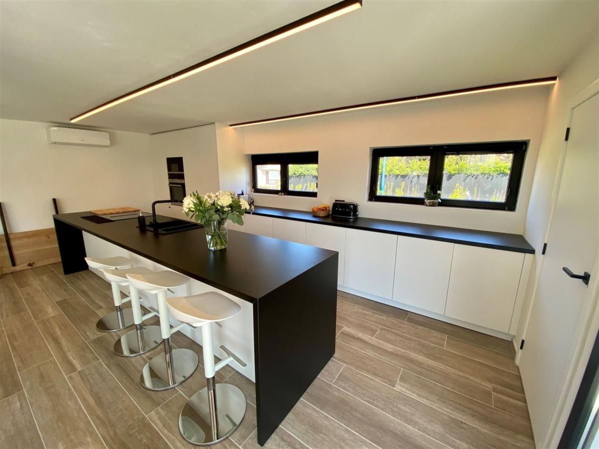 Moderne Kueche des Ferienhauses Petunias Deluxe in Sint-Idesbald, Westflandern, mit stilvoller Einrichtung und geraeumiger Kuecheninsel.