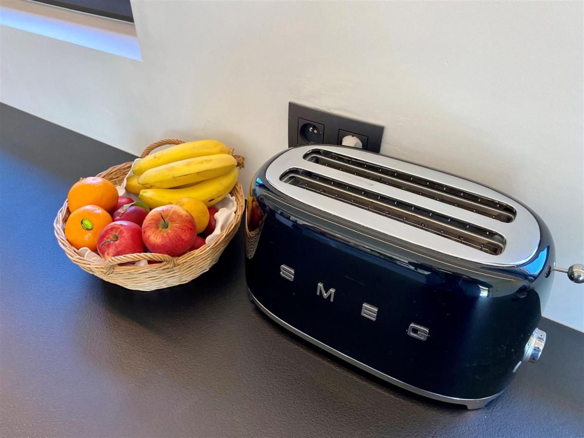 Moderne Kueche des Ferienhauses Petunias Deluxe in Sint-Idesbald, Westflandern, mit stilvollem SMEG-Toaster und Obstkorb.