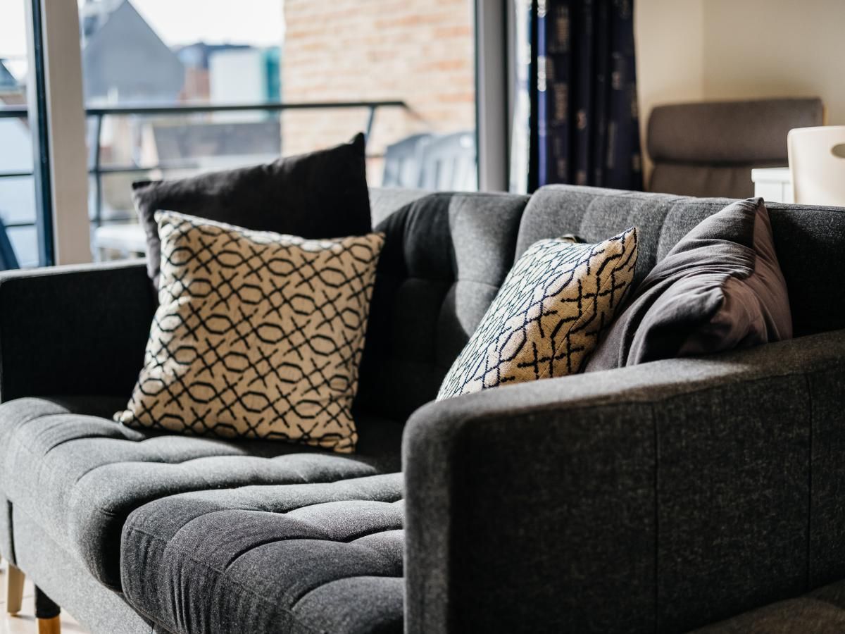 Gezellige zithoek in Cat Tweede vakantiehuis, Sint-Idesbald, West-Vlaanderen. Comfortabele bank met kussens en uitzicht op het terras.
