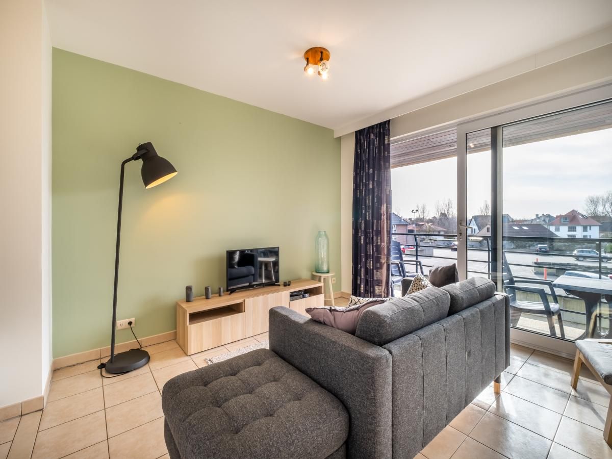 Gezellige woonkamer van vakantiehuis Cat Tweede in Sint-Idesbald, West-Vlaanderen, met moderne inrichting en ruim balkon met uitzicht.