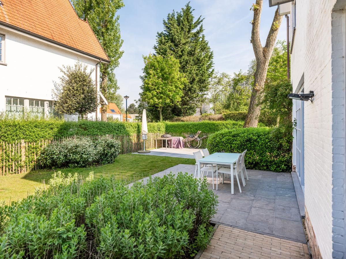 Geniet van de serene tuin van vakantiehuis La Matinee in Sint-Idesbald, West-Vlaanderen, met terras en groene omgeving.