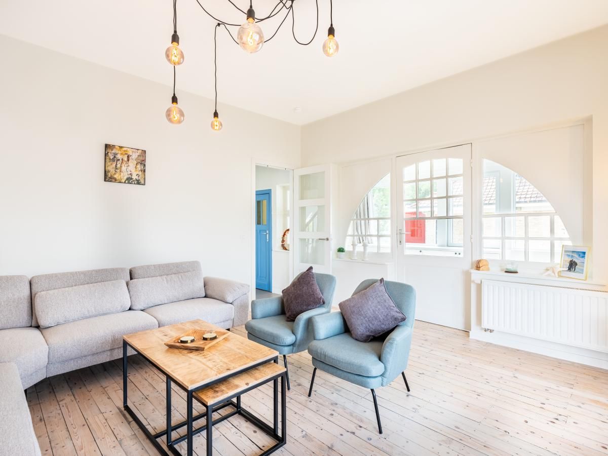 Stijlvolle woonkamer van La Classe vakantiehuis in Sint-Idesbald, West-Vlaanderen, Belgie met comfortabele zitruimte en veel natuurlijk licht.