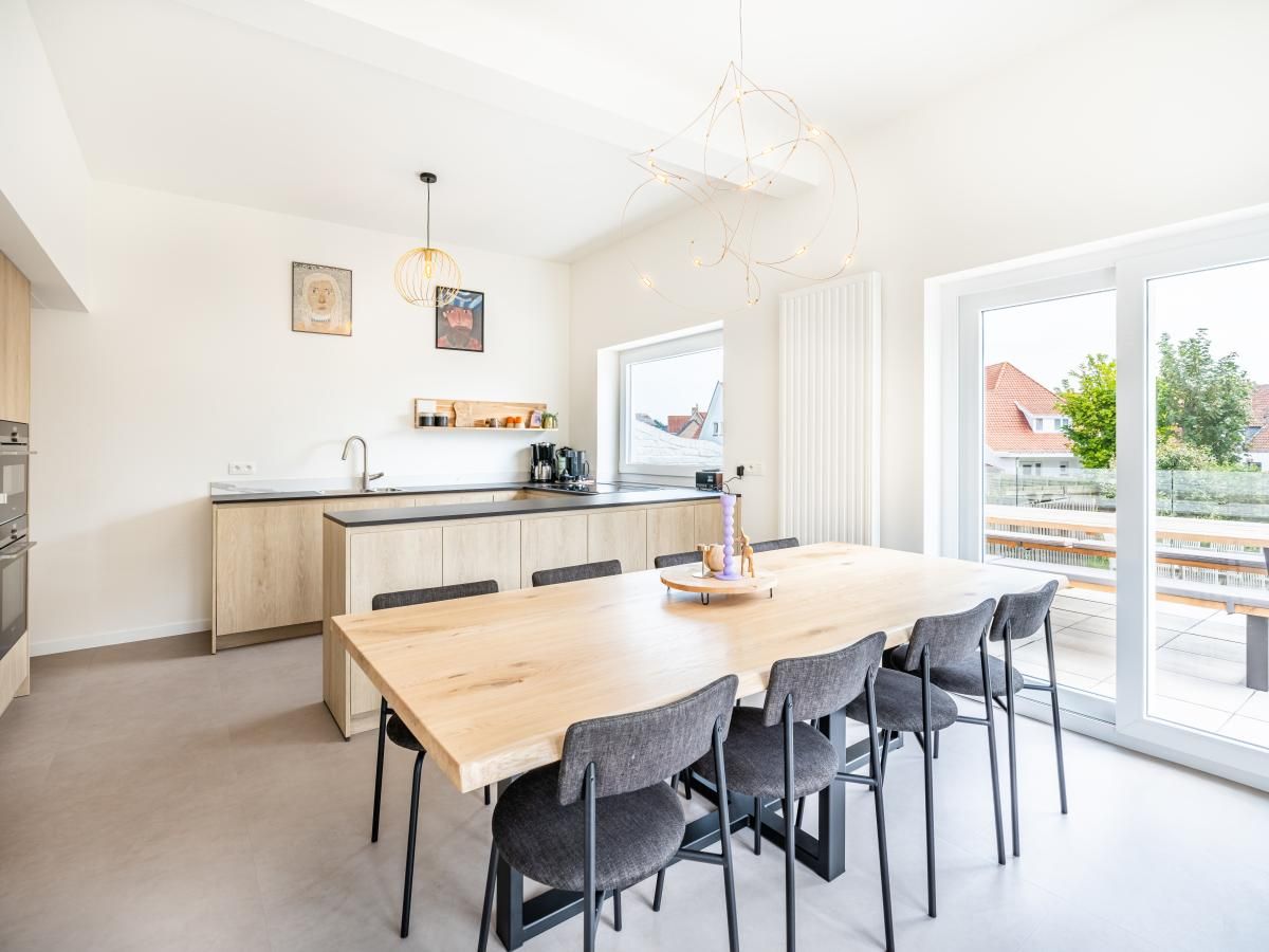 Moderne keuken en eetruimte in vakantiehuis La Classe, Sint-Idesbald, West-Vlaanderen met uitzicht op terras en tuin.