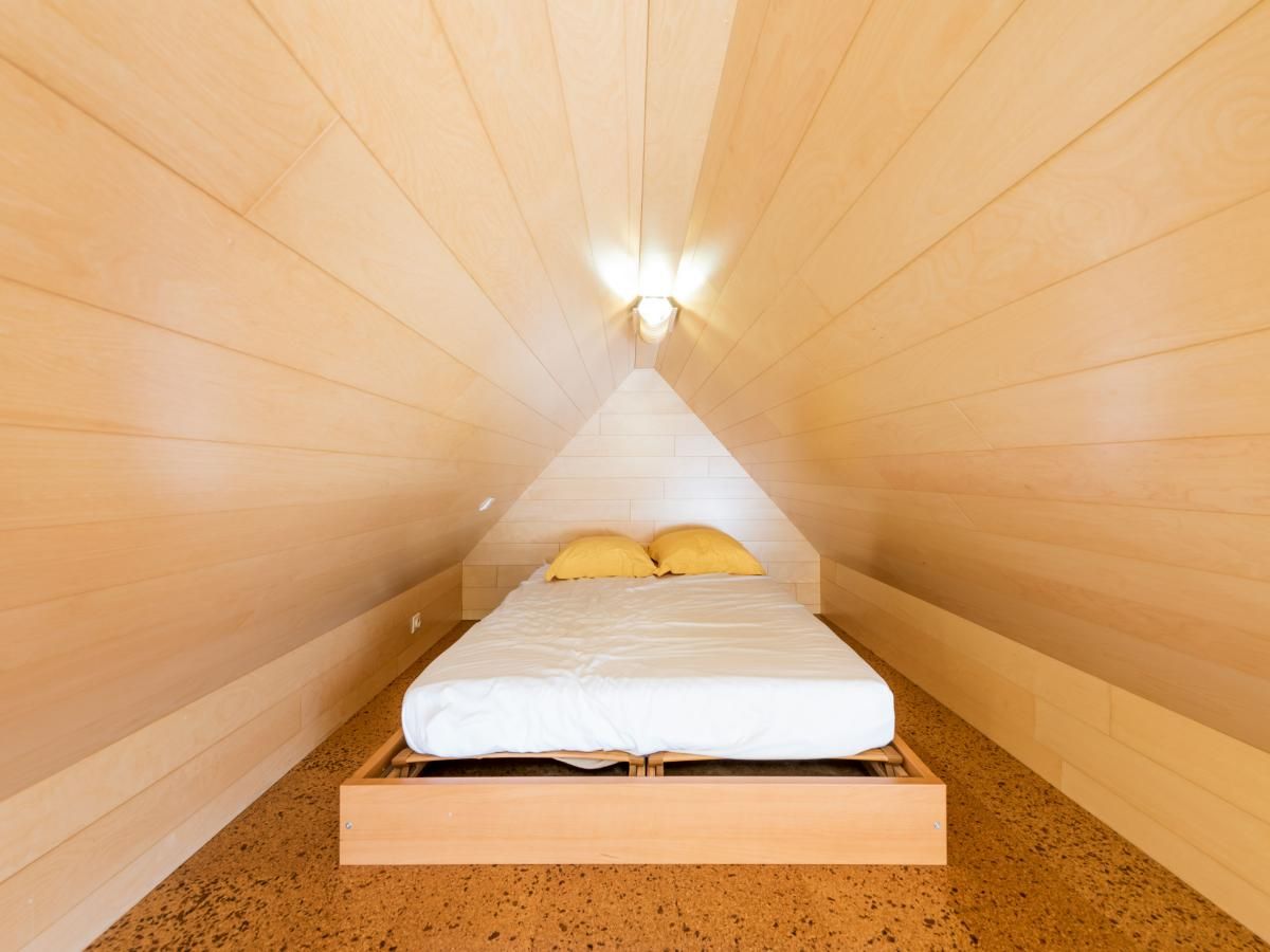 Knusse slaapkamer in Aubepine troisieme, vakantiehuis in Sint-Idesbald, West-Vlaanderen. Gezellige houten afwerking onder een schuin dak.
