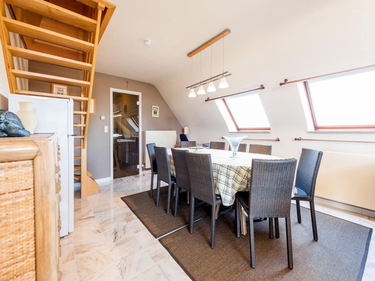 Gezellige eetkamer in vakantiehuis Aubepine troisieme, Sint-Idesbald, West-Vlaanderen. Ruime binnenruimte met houten trap en veel daglicht.