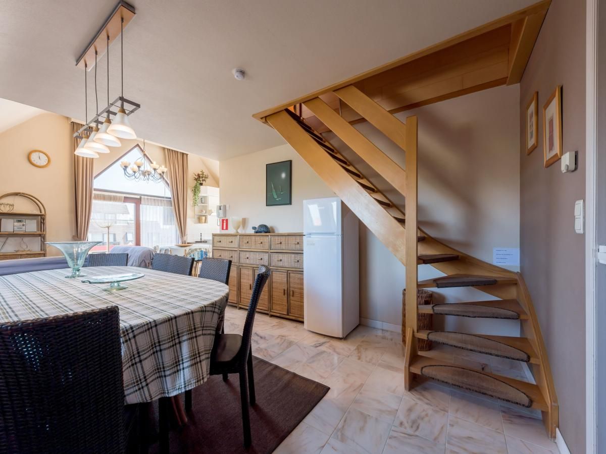 Ruime eetkamer in vakantiehuis Aubepine troisieme, Sint-Idesbald, West-Vlaanderen, met houten trap en sfeervolle inrichting.
