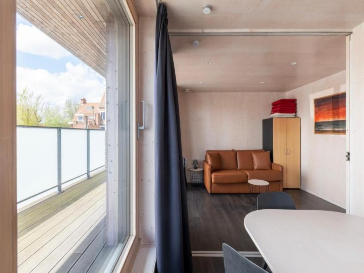 Gemuetlicher Innenbereich der Kruiers Eco Lodge in Middelkerke, Westflandern, mit Blick auf die Terrasse und den gemuetlichen Sitzbereich.