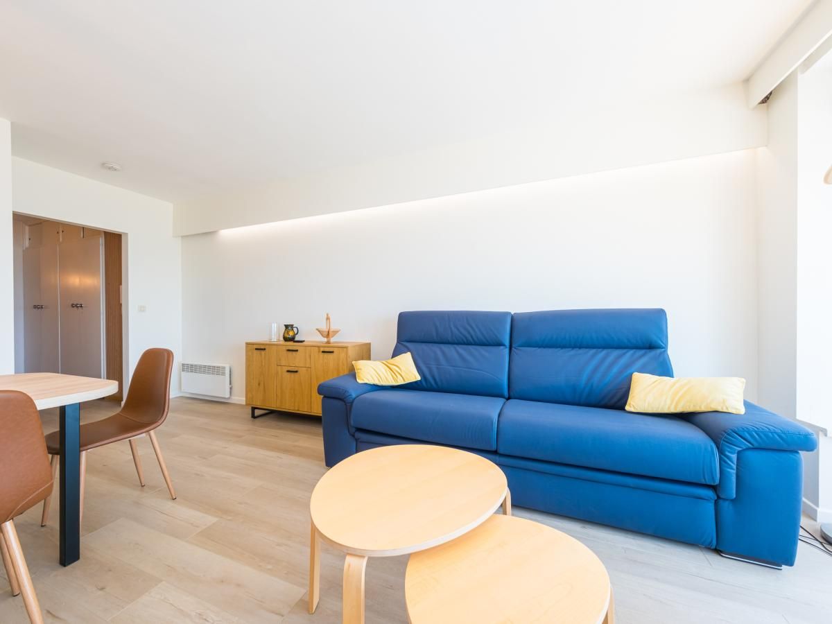 Modernes Wohnzimmer im Ferienhaus Reno - 0701 in Middelkerke, Westflandern mit bequemem blauen Sofa und Holzmoebeln.