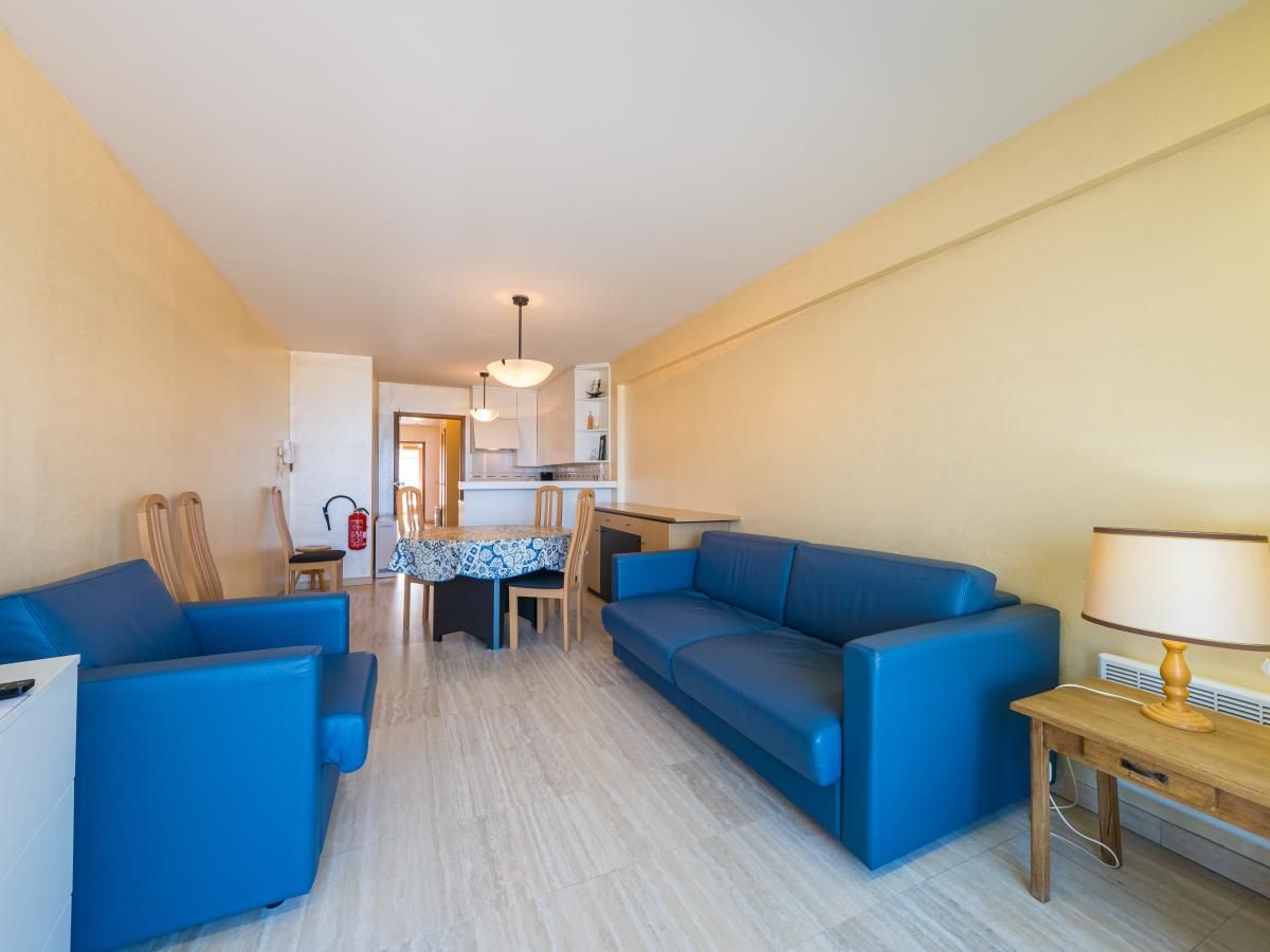 Helles Wohnzimmer im Azur Palace - 0602, Ferienhaus in Middelkerke, Westflandern, mit bequemen blauen Sofas und einer gemuetlichen Essecke.