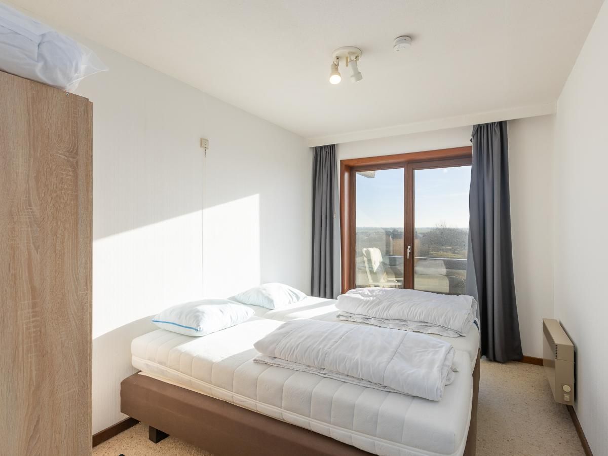 Helles Schlafzimmer in Dunekant - 0203 + park.6, Ferienhaus in Middelkerke, Belgien mit Blick auf die Terrasse und die Natur.