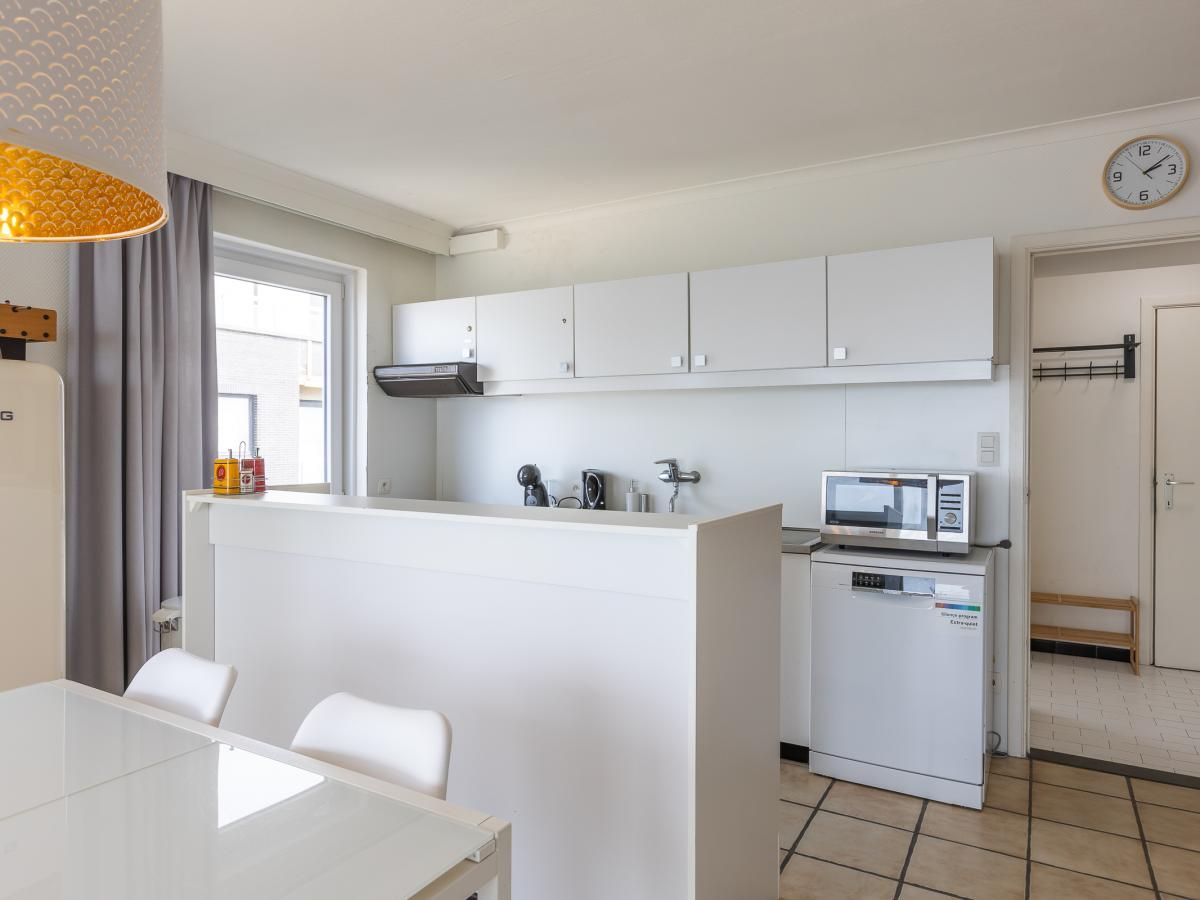 Moderne Kueche im Ferienhaus Kwintebank - 0904 in Middelkerke, Westflandern, Belgien, mit schlichten weissen Schraenken und Essbereich.