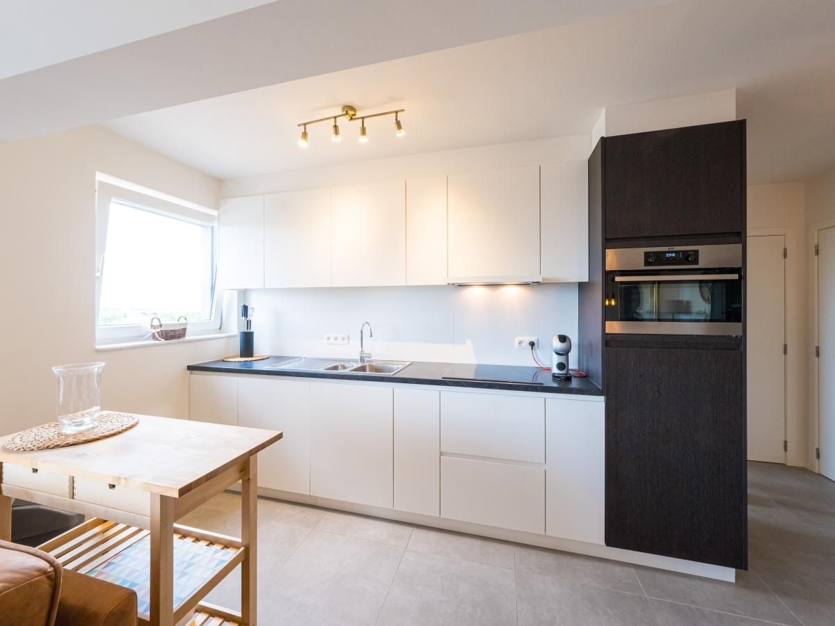 Moderne Kueche im Ferienhaus Majestic - 0505, Middelkerke, Westflandern, mit schlichten weissen Schraenken und viel natuerlichem Licht.