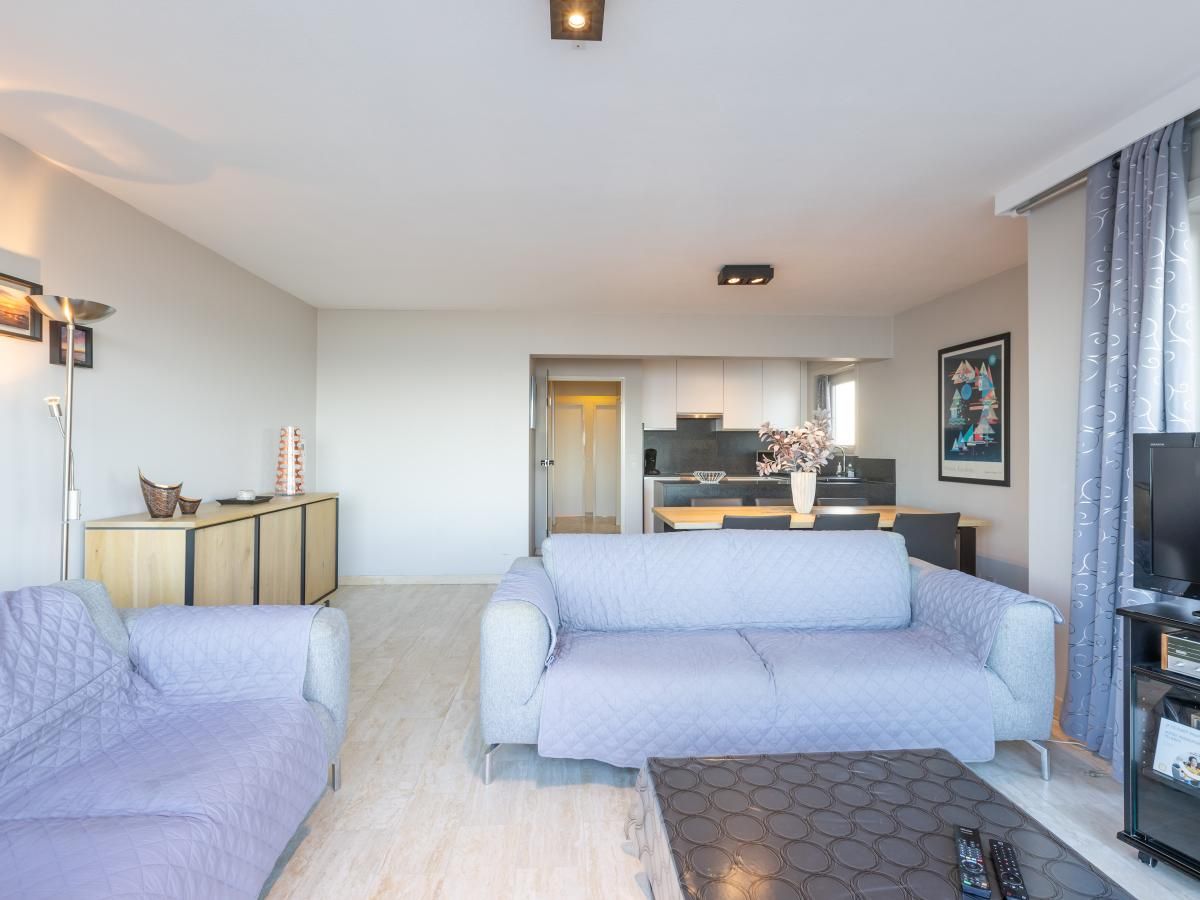 Helles Wohnzimmer im Ferienhaus Dunekant, Middelkerke, mit bequemen Sofas und moderner Kueche in Westflandern, Belgien.