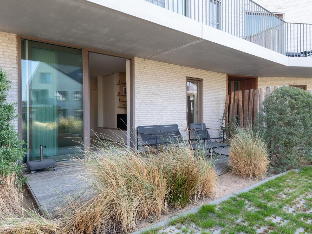 Veranda van West Bay vakantiehuis in Westende, West-Vlaanderen, met comfortabele zitplaatsen en groene omgeving.