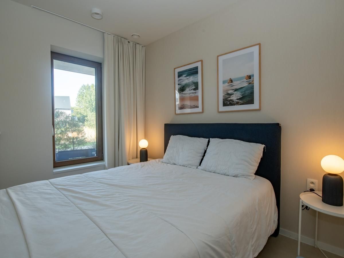 Sfeervolle slaapkamer in West Bay vakantiehuis, Westende, West-Vlaanderen, met comfortabel bed en rustgevend uitzicht op de tuin.