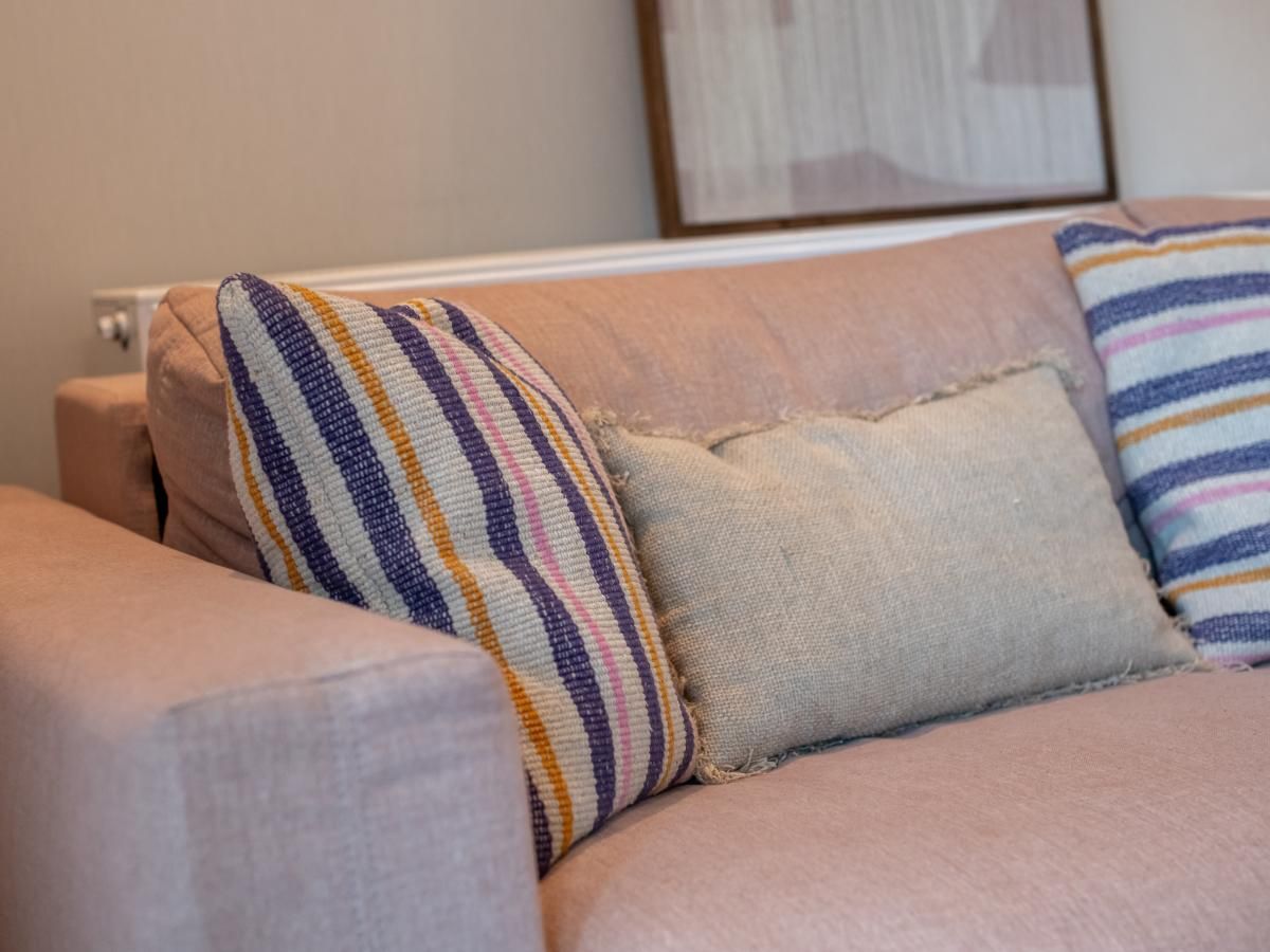 Gezellige woonkamer in vakantiehuis West Bay, Westende, Belgie, met kleurrijke kussens op de comfortabele bank.