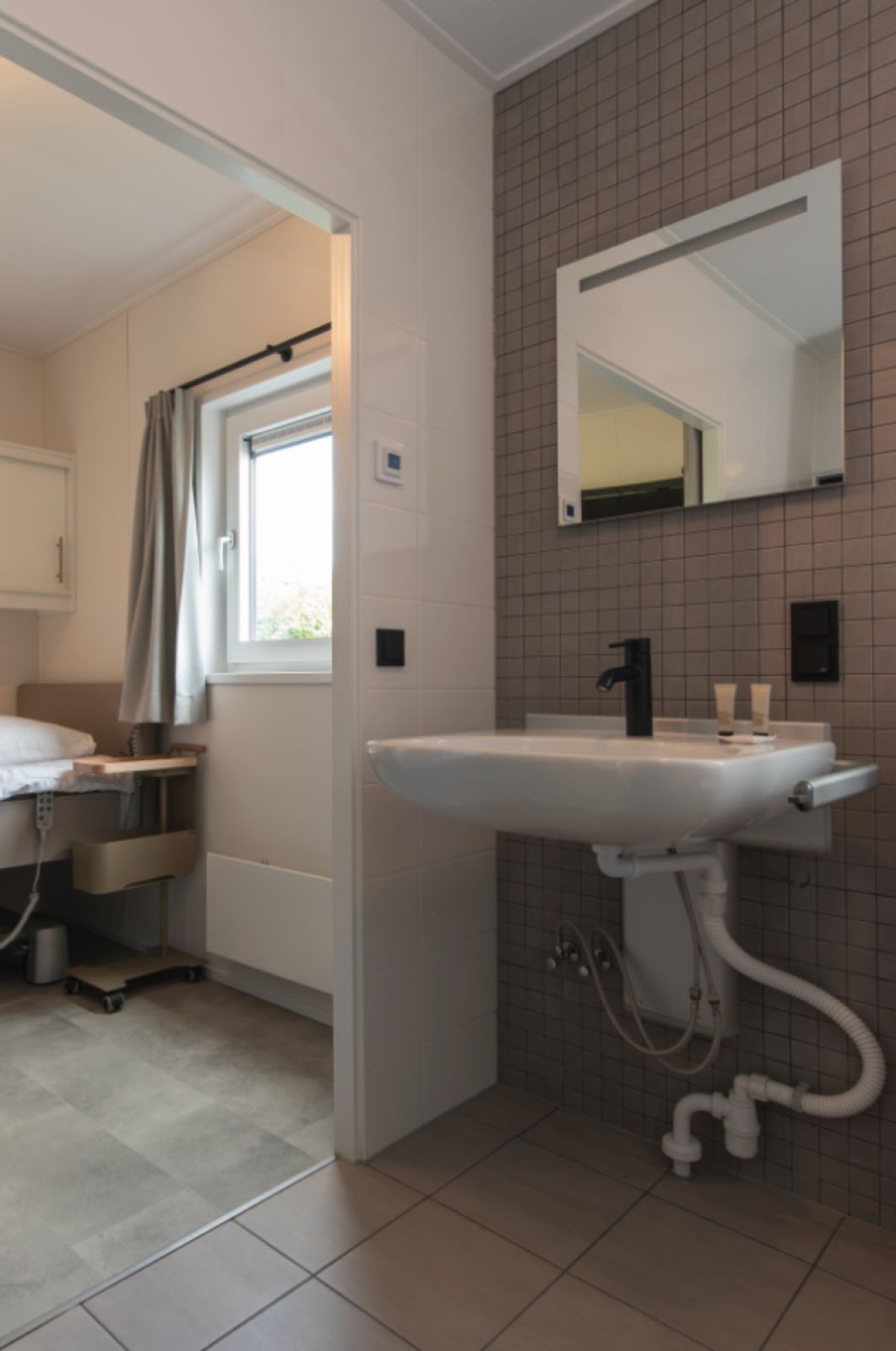Modernes Badezimmer in Access Lodge, einem Ferienhaus in Westende, Westflandern, mit stilvollem Waschbecken und natuerlichem Tageslicht.