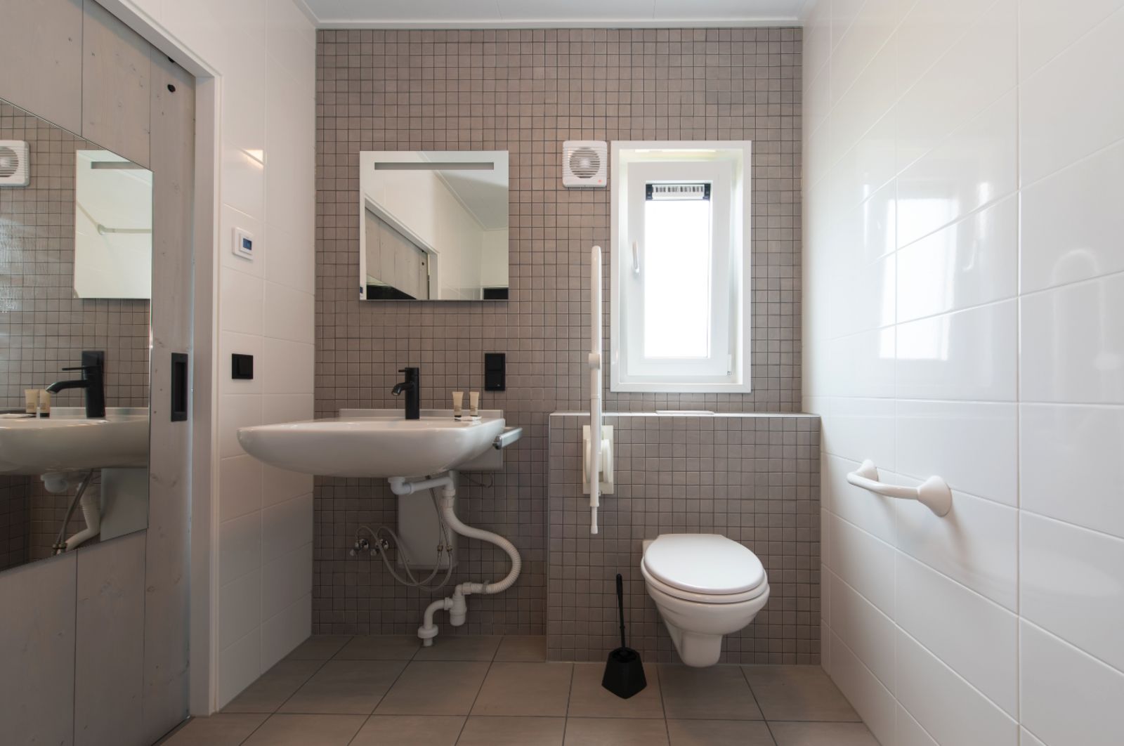 Modernes Badezimmer im Ferienhaus Access Lodge, Westende, Westflandern, mit stilvollen Fliesen und funktionalen Annehmlichkeiten.