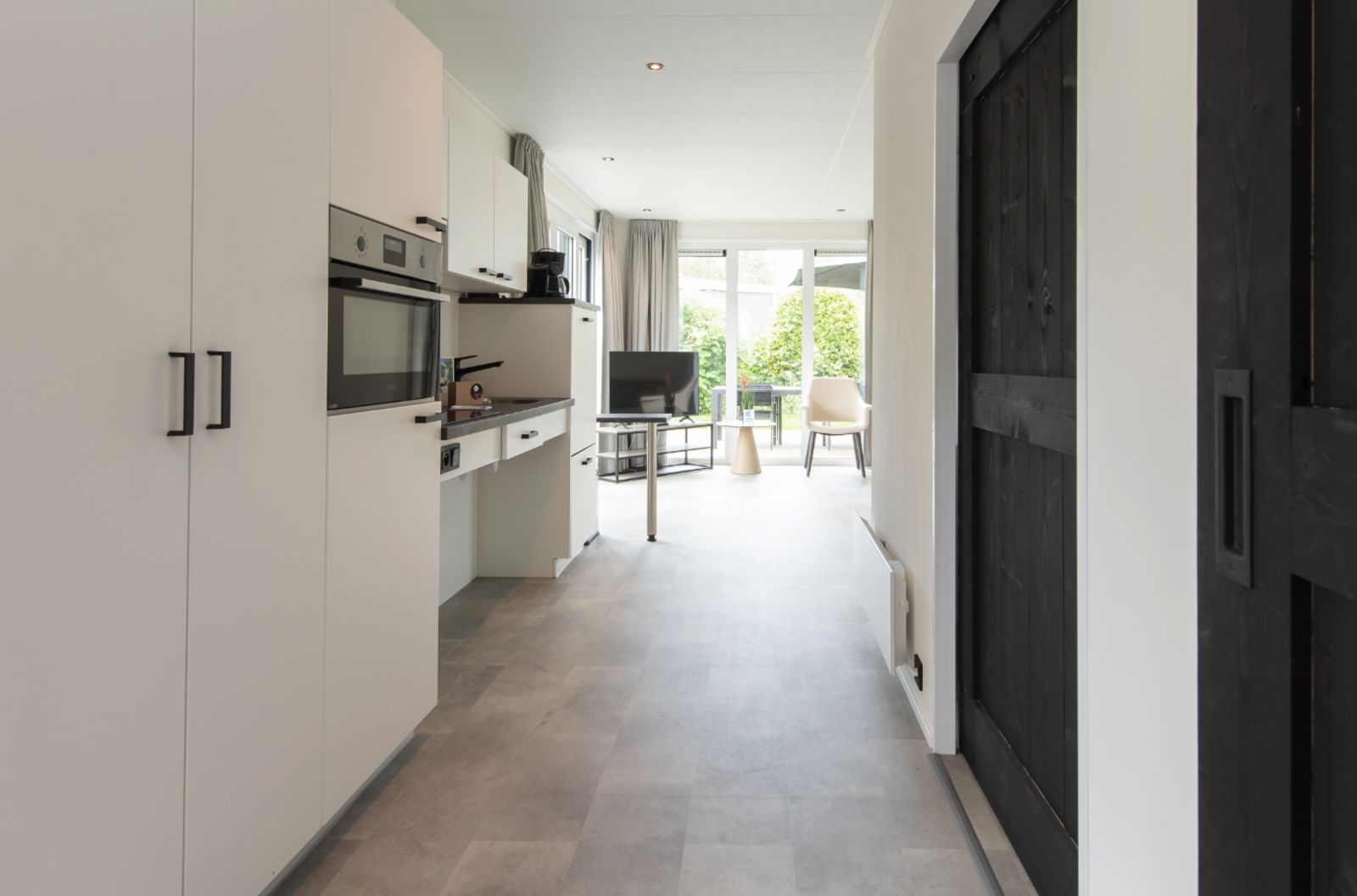 Moderne Kueche und Wohnzimmer von Access Lodge, einem Ferienhaus in Westende, Westflandern, mit Blick in den Garten.