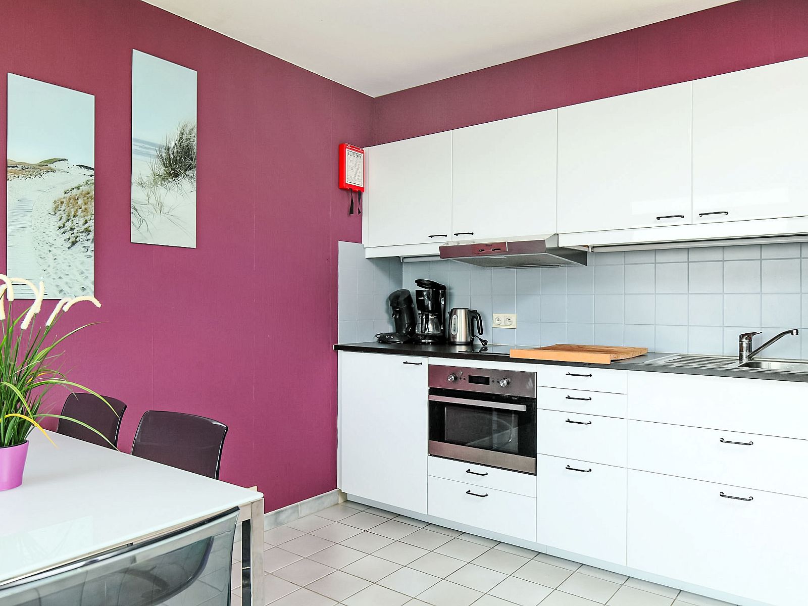 Moderne Kueche im Apartment Studio 604, Bredene, Westflandern, Belgien, mit stilvoller lila Wand und voll ausgestatteter Einrichtung.