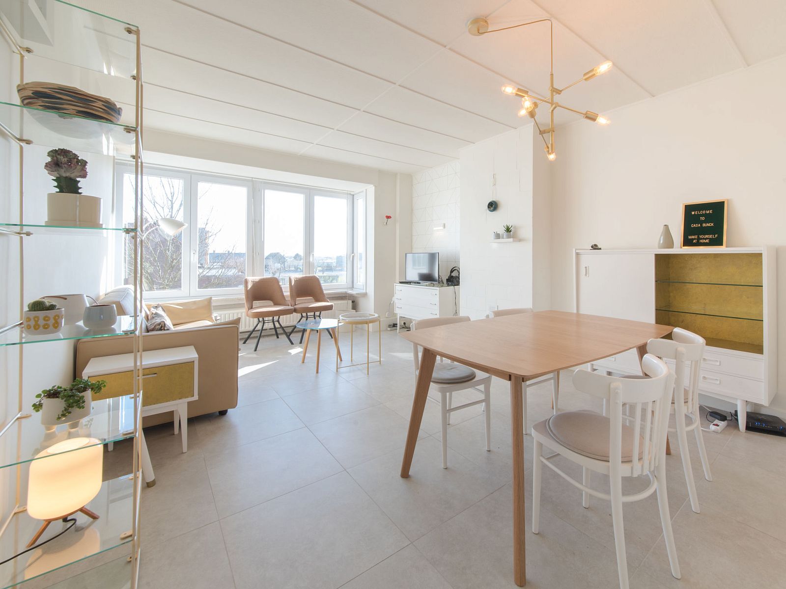 Helles Wohnzimmer des Apartments Casa Bunck in Bredene, Westflandern, Belgien, mit moderner Einrichtung und grossen Fenstern fuer viel natuerliches Licht.