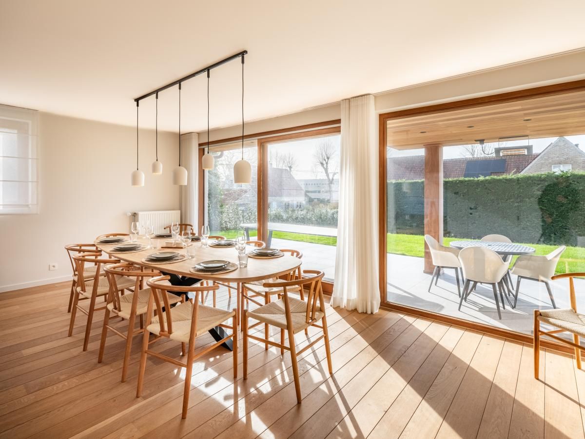 Helles Esszimmer im Ferienhaus "Pure Relax" in Oostduinkerke mit Blick auf die Terrasse und den Garten in Westflandern, Belgien.