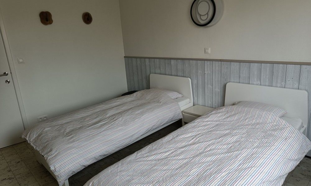 Papa's Dream vacation home in Oostduinkerke, bedroom with two single beds and wood paneling.