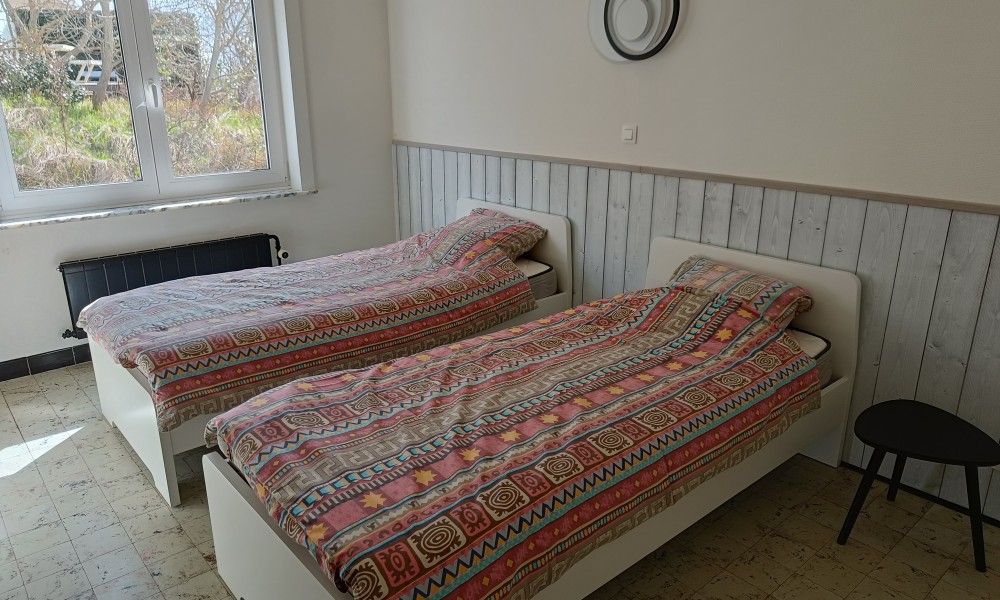 Bedroom in Papa's Dream vacation home, Oostduinkerke, with colorful blankets and lots of natural light.