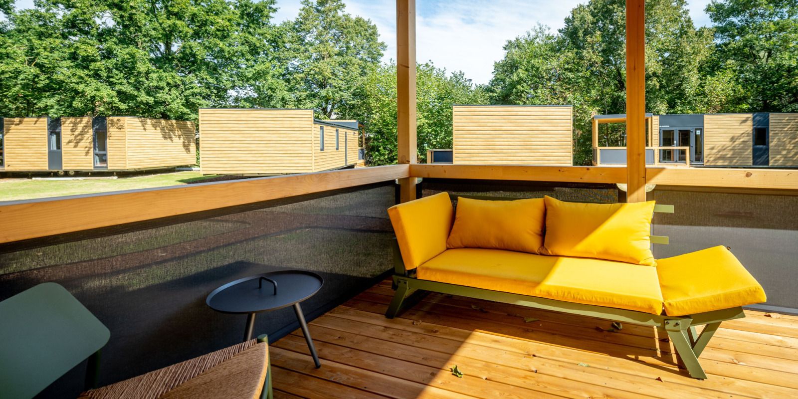Lodge-Veranda in Gent, Ostflandern, Belgien mit bequemen Sitzgelegenheiten und Blick auf die gruene Umgebung.