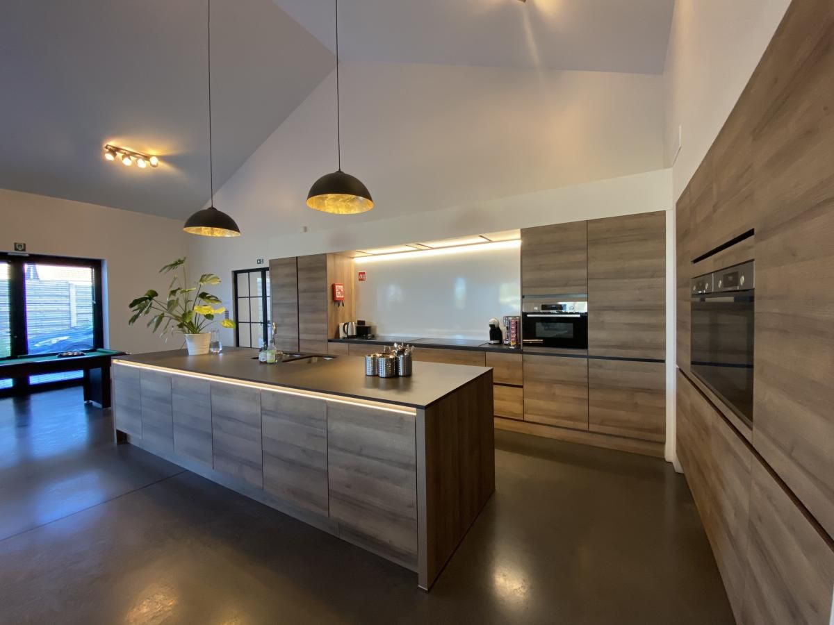 Moderne Kueche in der Villa Mareon, einem Ferienhaus in Maarkedal, Ostflandern, mit eleganten Holzoberflaechen und grosszuegiger Raumaufteilung.